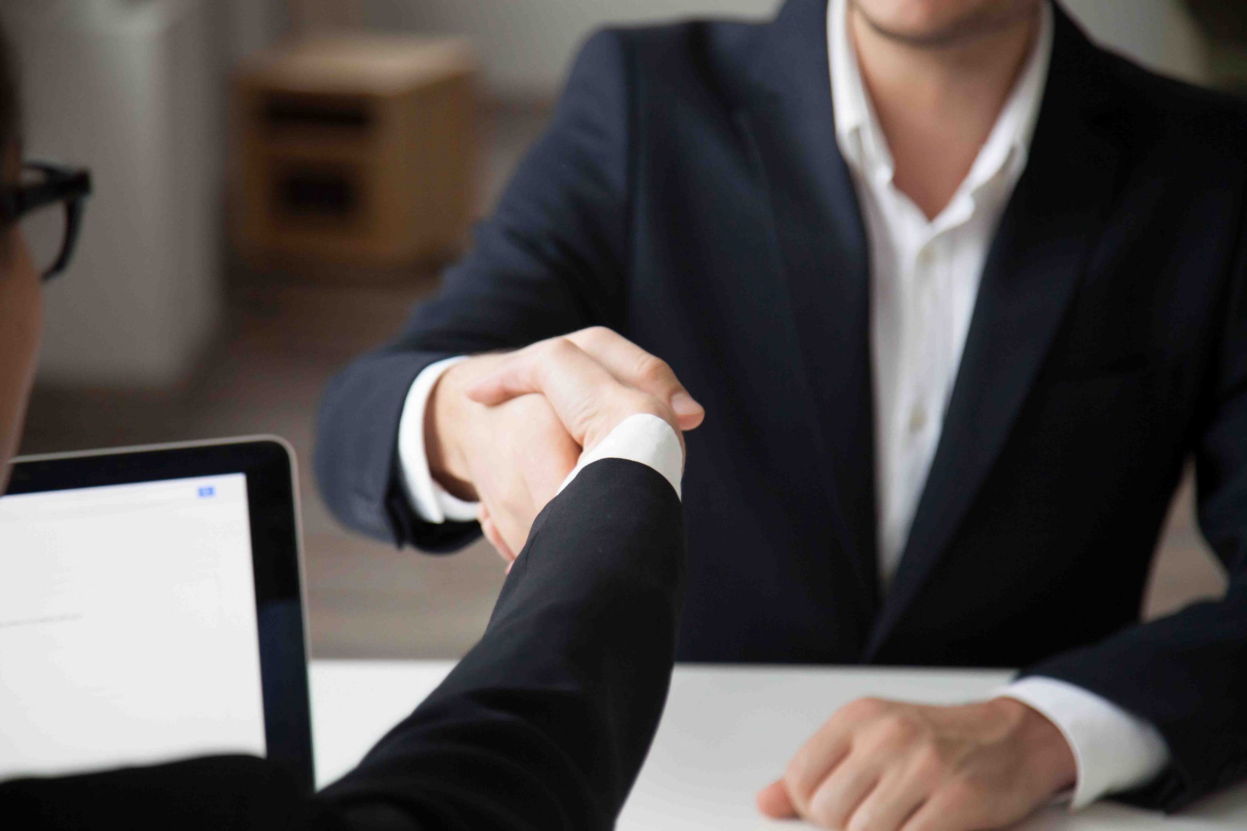 Close up of CEO shaking hand of male job applicant during recruitment process in modern office. Business partners greeting with handshake at first corporate meeting. Concept of cooperation partnership